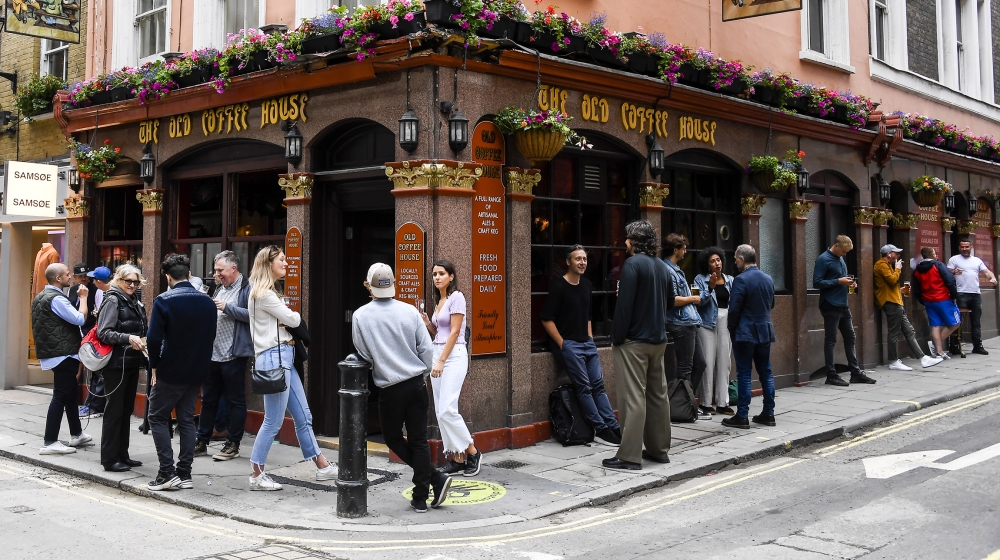 People stand outside a pub in Soho, as the capital is set to reopen after the lockdown due to the Coronavirus outbreak, in London, Saturday, July 4, 2020. England is embarking on perhaps its biggest l