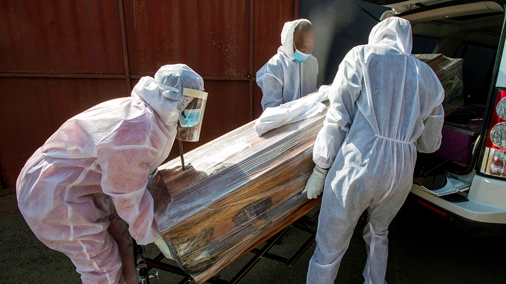 Maziya funeral home workers in protective suits carries a confine of a woman who died  from COVID-19 unto a hearse in Katlehong,  near Johannesburg, South Africa, Tuesday, July 21, 2020. South Africa,
