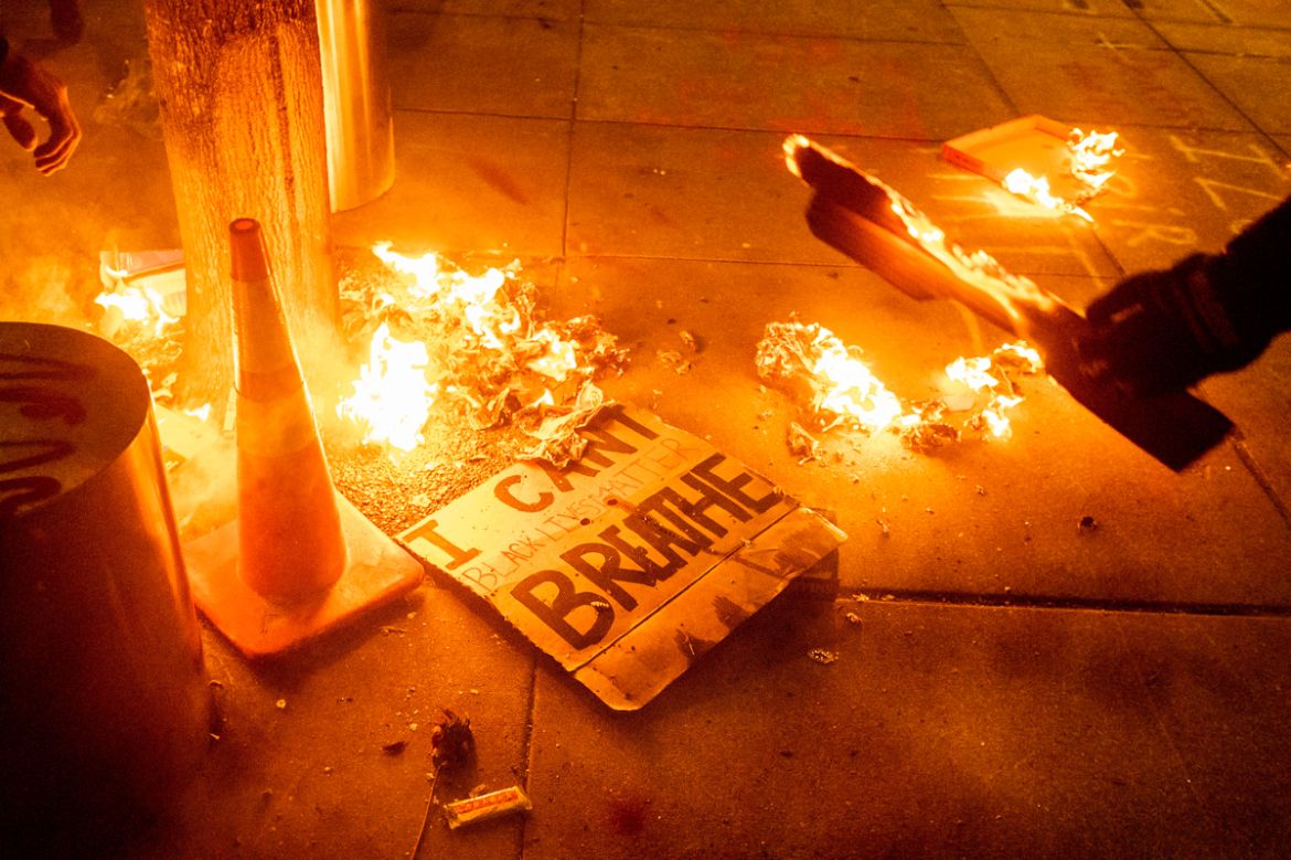 A Black Lives Matter protester burns a sign outside the Mark O. Hatfield United States Courthouse on July 21, 2020, in Portland, Ore. (AP Photo/Noah Berger)