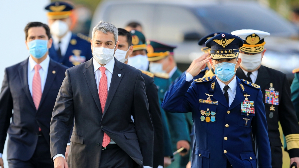 President Mario Abdo Benitez and members of his government wear face masks as they arrive for a ceremony in tribute to veterans of the 1932-1935 Chaco War, at the La Victoria barracks in San Lorenzo