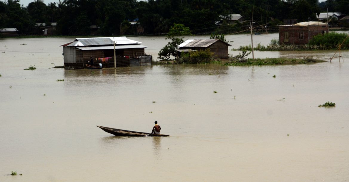 epa08551695 A man rows his boat near partially submerged houses in Morigaon district of Assam, India, 17 July 2020. According to news reports, Assam state continues to battle with flood situation whic