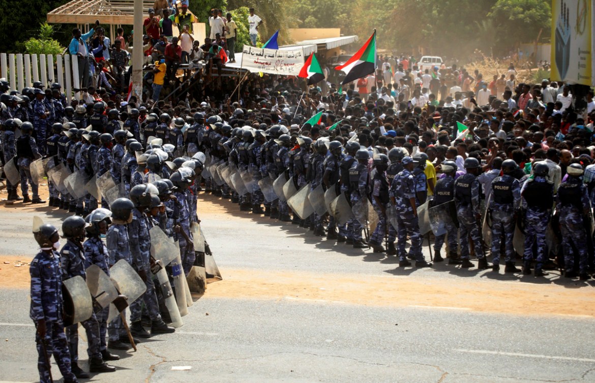 Riot police officers hold position against protesters near the Parliament buildings, as members of Sudanese pro-democracy protest on the anniversary of a major anti-military protest, as groups loyal t