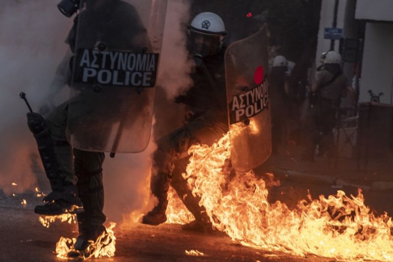 Riot police officers try to avoid patrol bombs thrown by protesters outside the Greek Parliament during a demonstration against new protest law in Athens, on Thursday, July 9, 2020. Violence has broke