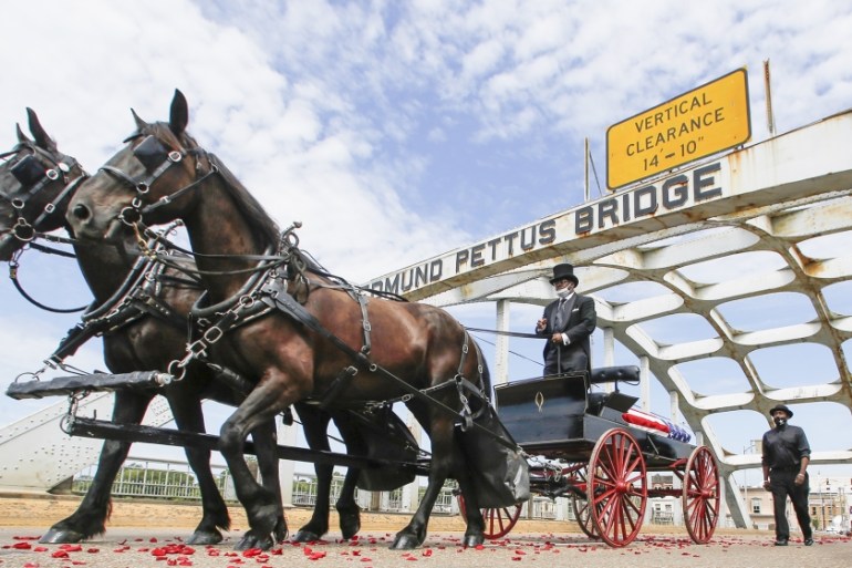 The casket of Rep. John Lewis moves over the Edmund Pettus Bridge by horse drawn carriage during a memorial service for Lewis, Sunday, July 26, 2020, in Selma, Ala. Lewis, who carried the struggle aga