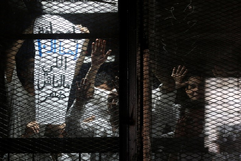 Zeid looks on with other journalists behind bars during their trial at a court on the outskirts of Cairo