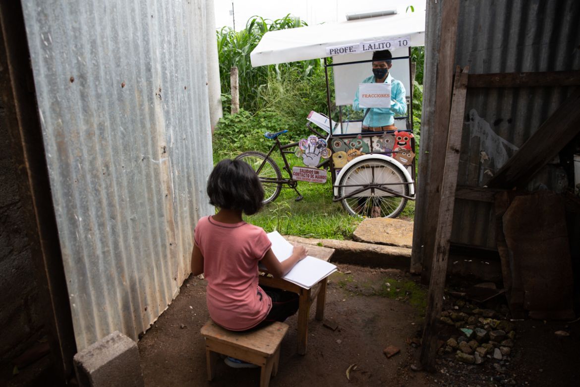 Gerardo Ixcoy teaches 12-year-old student Paola Ximena Conoz about fractions from his mobile classroom, parked just outside the door to her home in Santa Cruz del Quiche, Guatemala, Wednesday, July 15