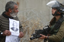 A Palestinian demonstrator holds portraits of late South African Leader Nelson Mandela a
