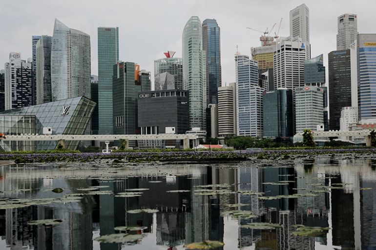 epa08544543 The skyline of the financial district reflected in a lotus pond next to the ArtScience Museum in Singapore, 14 July 2020. Singapore''s economy shrank a record 41.2 percent as a result of th