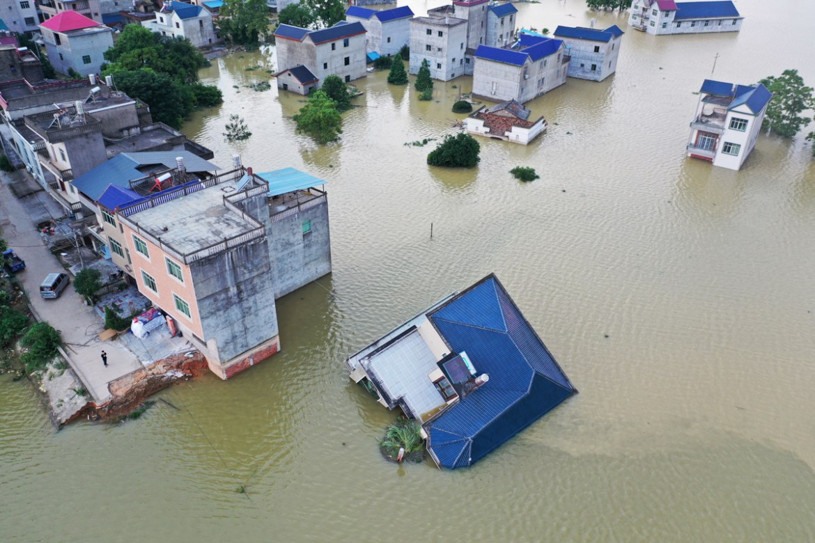 A building that has fallen over after flooding is seen partially submerged in floodwaters following heavy rainfall in the region, at a village near Poyang Lake, in Poyang county, Jiangxi province, Chi