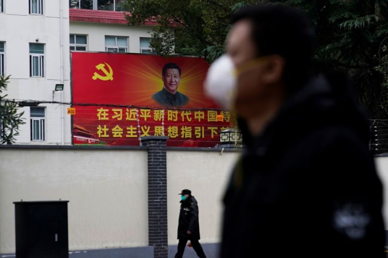 People wearing masks walk past a portrait of Chinese President Xi Jinping on a street as the country is hit by an outbreak of the novel coronavirus in Shanghai