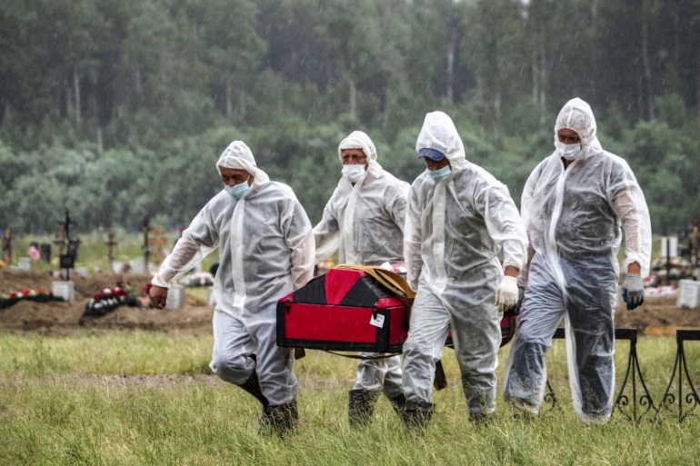 Cemetery workers wearing protective suits carry the coffin of a COVID-19 victim in the special purpose for coronavirus victims section of a cemetery in Kolpino, outside St.Petersburg, Russia, Tuesday,