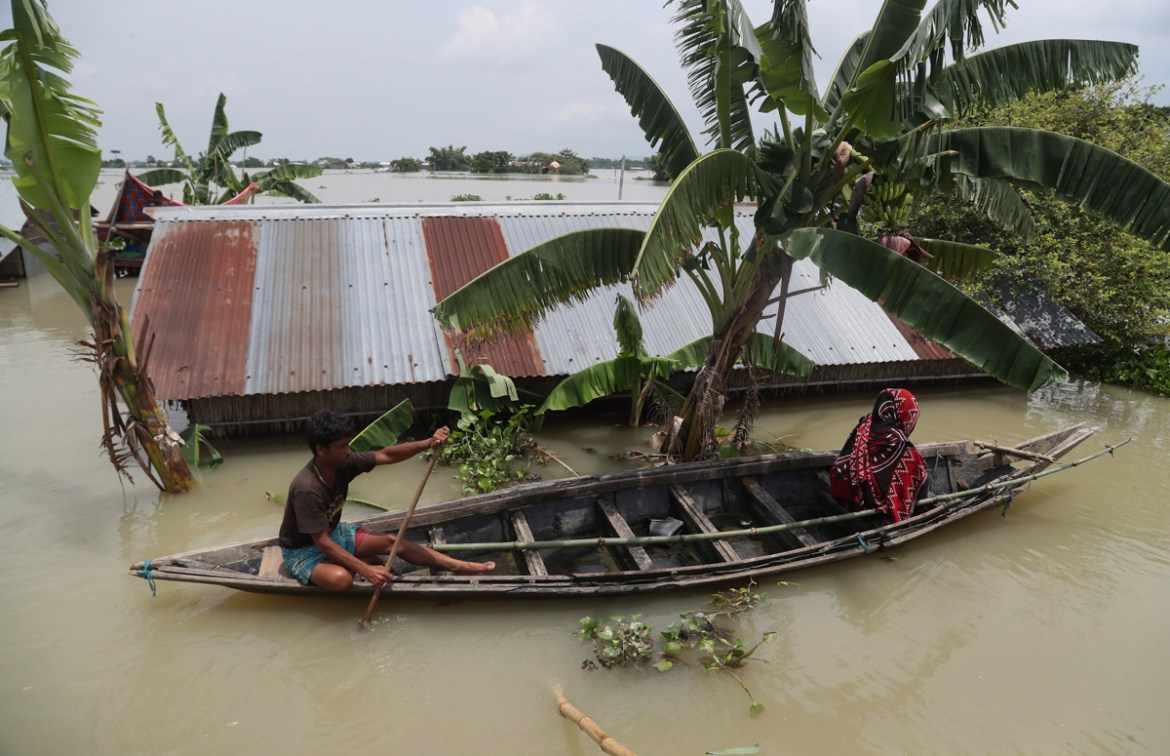 An Indian flood affected man and a woman ride on a country boat in Gagolmari village, Morigaon district, Assam, India, Tuesday, July 14, 2020. Hundreds of thousands of people have been affected by flo