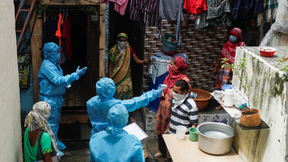 A healthcare worker checks the temperature of a resident during a medical campaign for the coronavirus disease (COVID-19) at a slum area in Mumbai