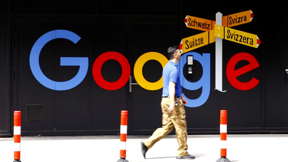 A man walks past a logo of Google in Zurich