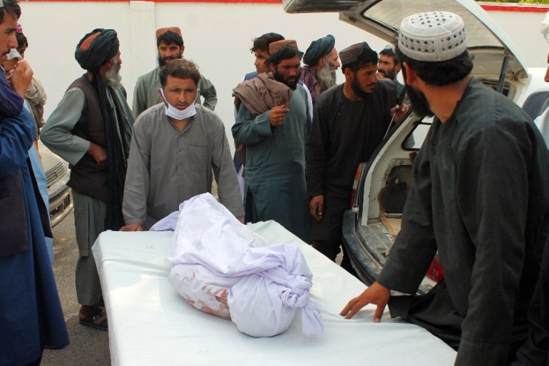 Afghans carry the body of a man who was killed during a deadly attack, in the southern Helmand province, Monday, June 29, 2020. A car bombing and mortar shells fired at a busy market in Helmand