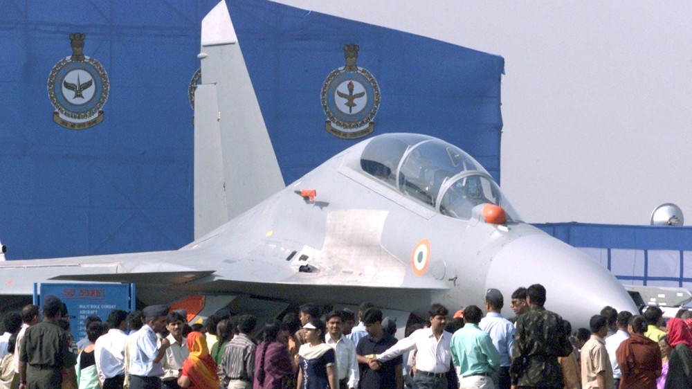 Indian visitors stand besides a SU-30 MKI fighter jet