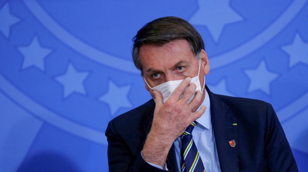 Brazil's President Jair Bolsonaro adjusts his protective face mask during the inauguration ceremony of the new Communications Minister Fabio Faria (not pictured) at the Planalto Palace, in Brasilia, B