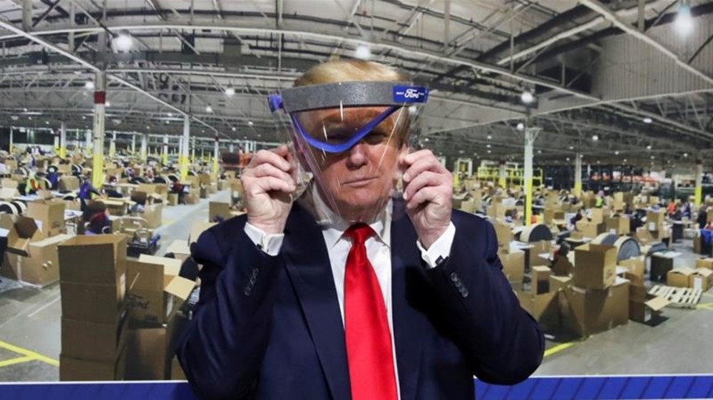 Trump holds up a protective face shield during a behind-the-scenes tour of a Ford facility in Michigan in May [File: Leah Millis/Reuters]