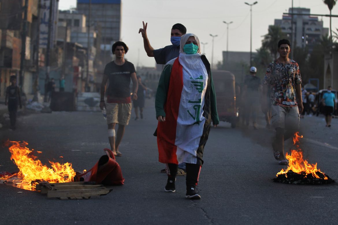 Iraqi demonstrators are pictured as others clash with security forces in al-Tayaran square in central Baghdad on July 27, 2020 during the ongoing anti-government protest due to poor public services. (