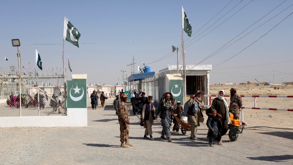 Pakistani soldiers keep guard as citizens return from Afghanistan at the border-crossing town of Chaman