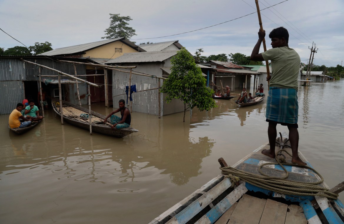 An Indian flood affected man rows a boat near partially submerged houses in Gagolmari village, Morigaon district, Assam, India, Tuesday, July 14, 2020. Hundreds of thousands of people have been affect