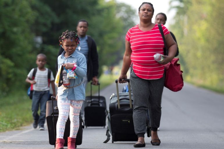 A family that stated they are from Haiti walk to the US-Canada border to cross into Canada from Champlain, New York