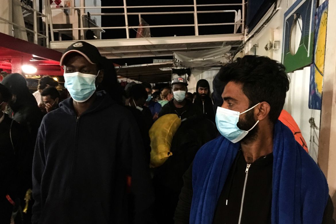 Migrants wearing protective facemasks on board of the humanitarian aid boat Ocean Viking, chartered by charity group SOS Mediterranee, prepare to disimbark upon their arrival on July 6, 2020 in the ha