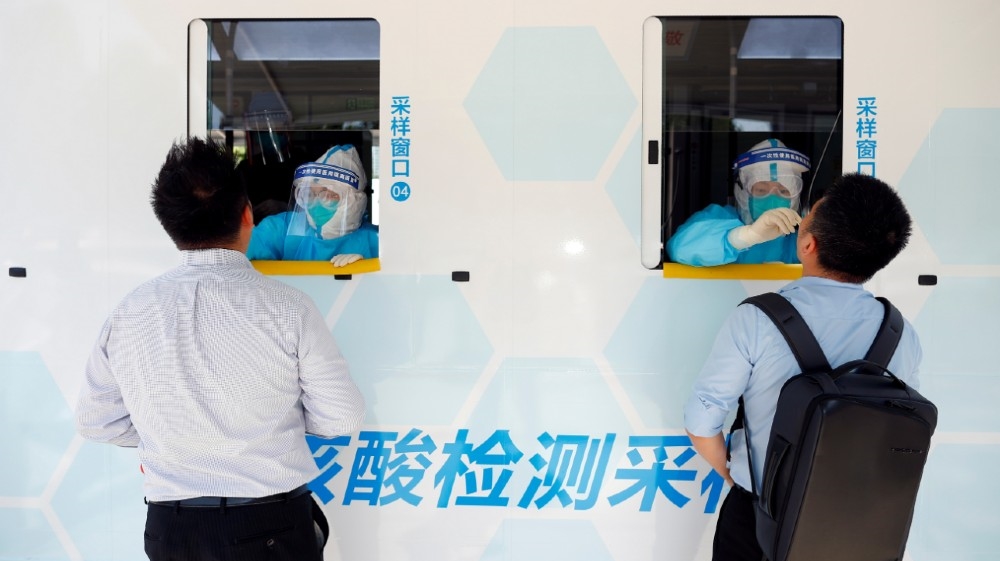 Two people are tested at the windows of a testing vehicle, following a new outbreak of the coronavirus disease (COVID-19) in Beijing, China, June 30, 2020. REUTERS/Thomas Peter