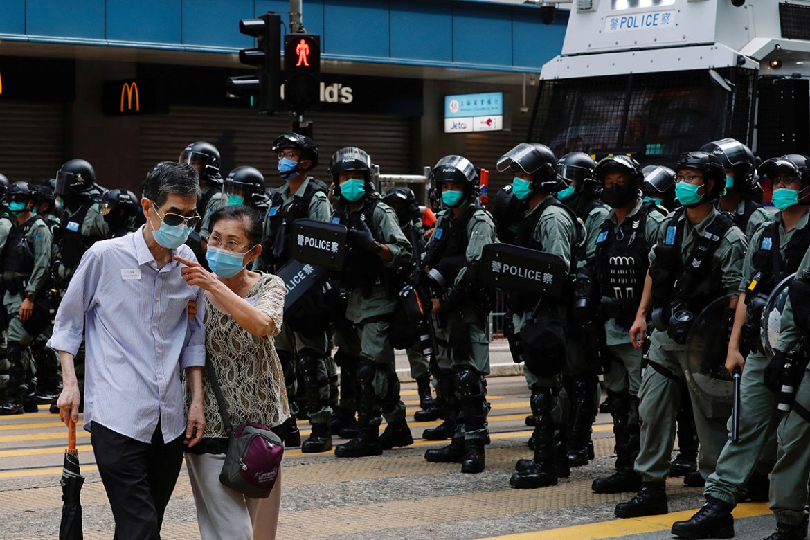 A couple walks past riot police as anti-national security law protesters march during the anniversary of Hong Kong''s handover to China from Britain, in Hong Kong, China July 1, 2019. REUTERS/Tyrone Si