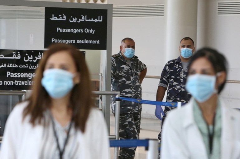 Health workers and members of internal security forces wearing face masks stand inside Beirut international airport