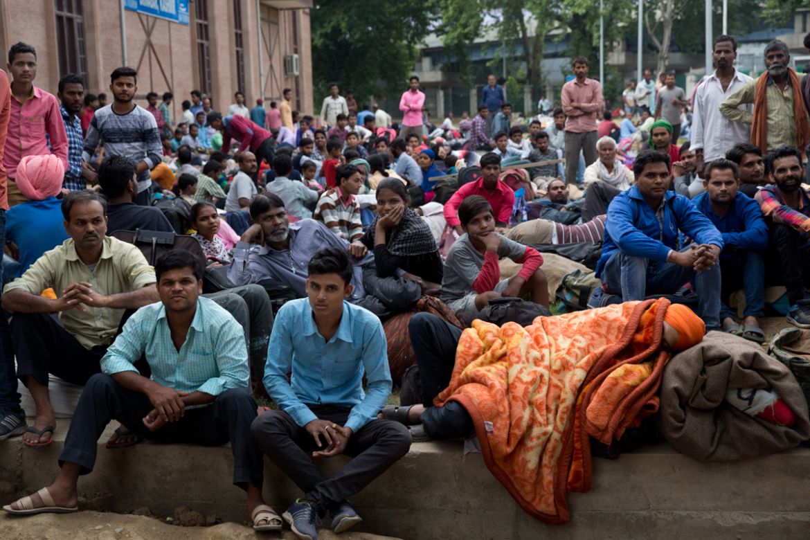 In this Tuesday, Aug. 6, 2019 photo, Indian migrant workers wait outside the government transport yard waiting to buy bus tickets to leave the region, during curfew in Srinagar, Indian controlled Kash