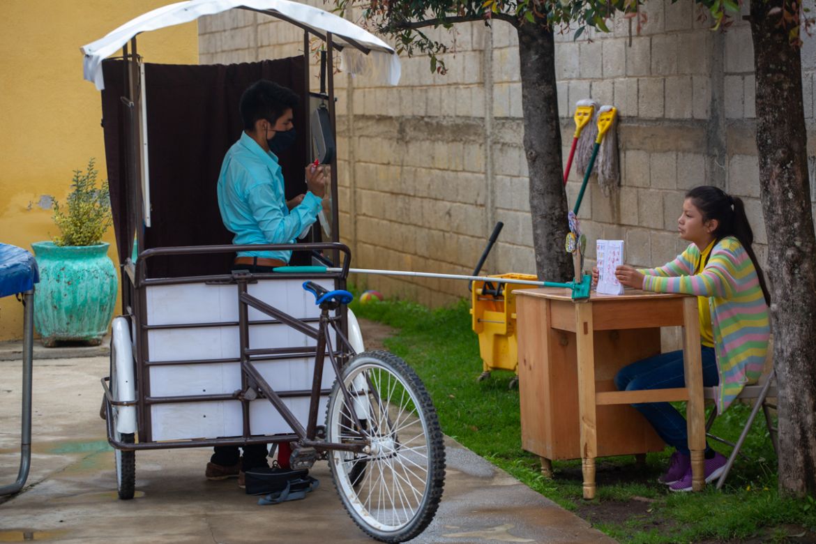 Gerardo Ixcoy teaches fractions to 14-year-old Brenda Morales, from his secondhand adult tricycle that he converted into a mobile classroom, in Santa Cruz del Quiche, Guatemala, Wednesday, July 15, 20
