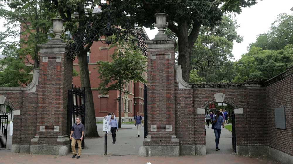 Pedestrians walk through the gates of Harvard Yard at Harvard University in Cambridge, Mass., Tuesday, Aug. 13, 2019. (AP Photo/Charles Krupa)