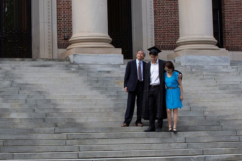 epa08450052 Harvard College Class of 2020 Graduate Tyler Yan (C) along with his parents James Yan (L) Min Chang (R) pose for photo on the stairs of the Widener Library on what would have been the 369t
