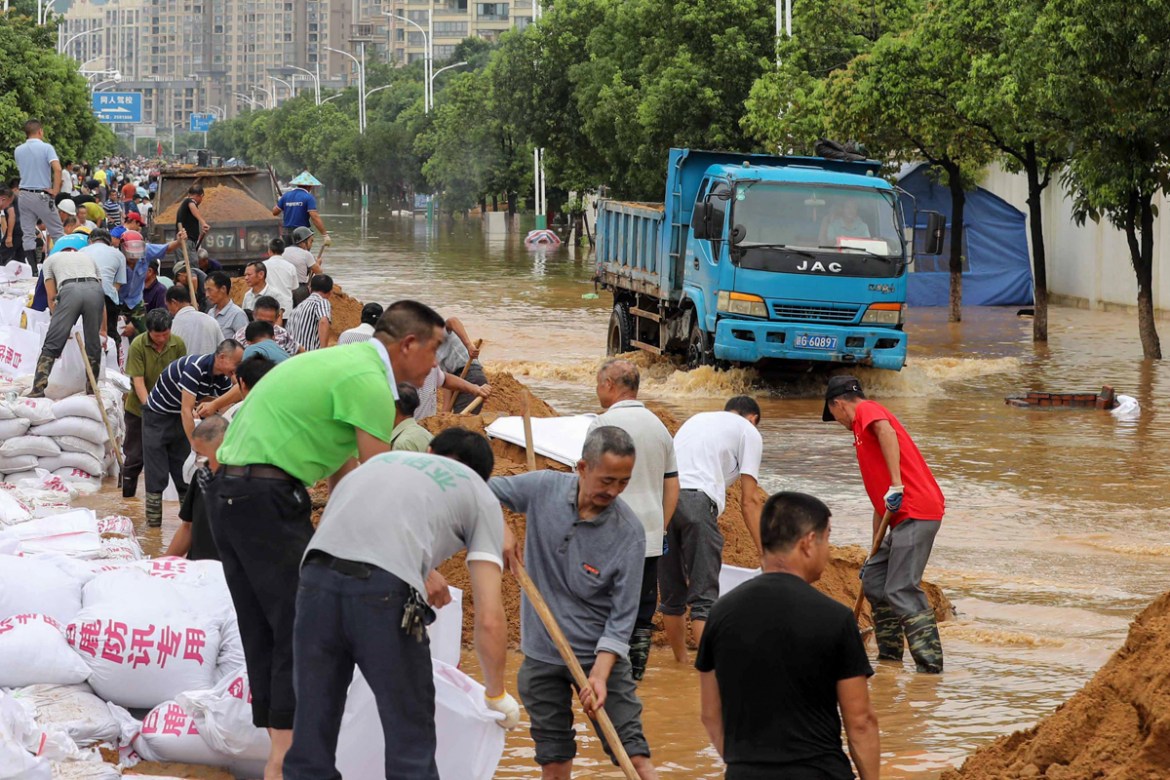 People build anti-flood barriers next to a flooded street in Jiujiang in China''s central Jiangxi province on July 13, 2020. - Floods across central and eastern China have left more than 140 people dea