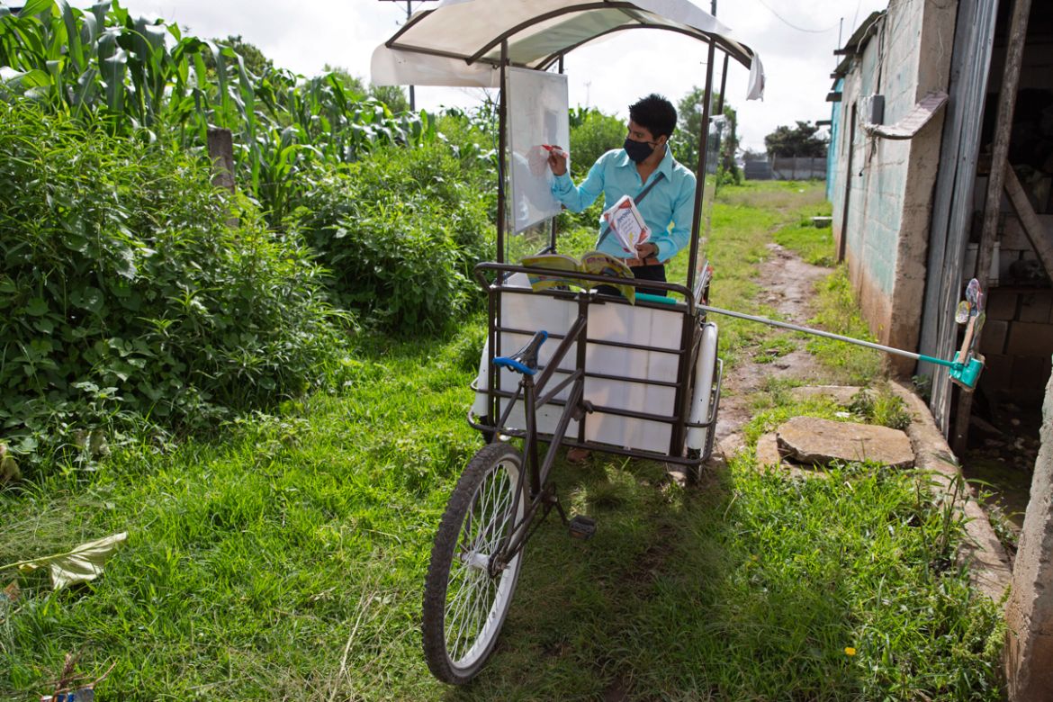 Teacher Gerardo Ixcoy conducts a math class from a secondhand, adult tricycle that he converted into a mobile classroom, in Santa Cruz del Quiche, Guatemala, Wednesday, July 15, 2020, amid the new cor