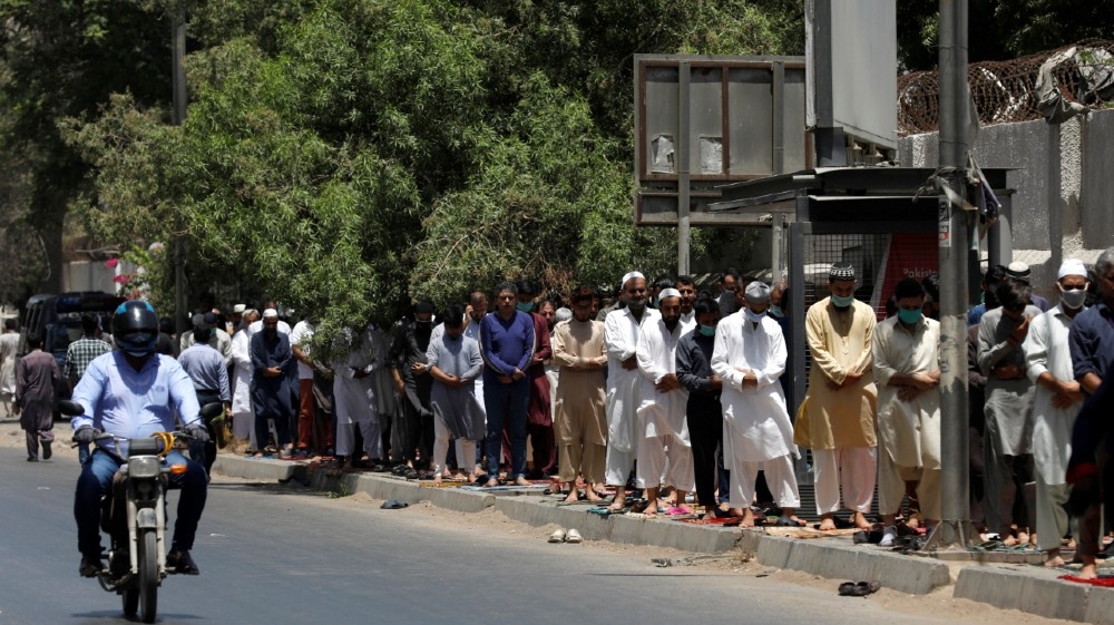 People attend Friday prayers along a sidewalk at a business area, after Pakistani authorities re-imposed lockdowns in selected areas in an effort to stop the spread of
