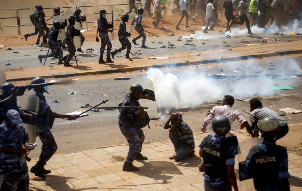 Riot police officers disperse protesters near the Parliament buildings, as members of Sudanese pro-democracy protest on the anniversary of a major anti-military protest, while groups loyal to toppled