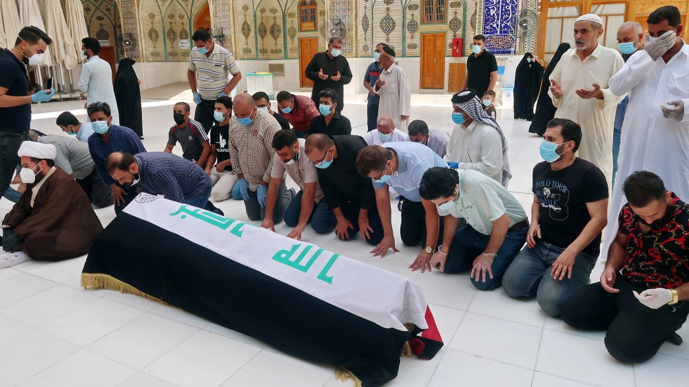 Mourners pray near the coffin of Hisham al-Hashemi during the funeral in Najaf