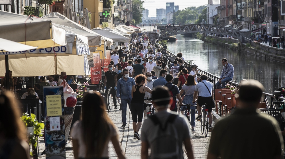 People take a walk and relax at the Naviglio Grande canal, in Milan, Italy, Sunday, May 24, 2020. Europeans and Americans soaked up the sun where they could, taking advantage of the first holiday week