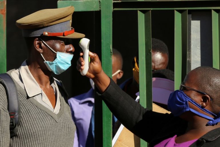 A person checks a policeman''s temperature during a nationwide lockdown to help curb the spread of the coronavirus disease (COVID-19) in Harare