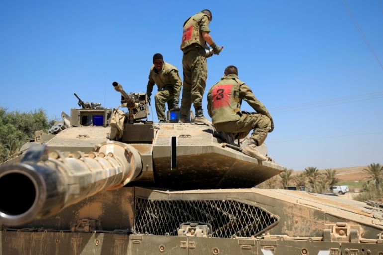 Israeli soldiers stand atop a tank near the border between Israel and the Gaza Strip