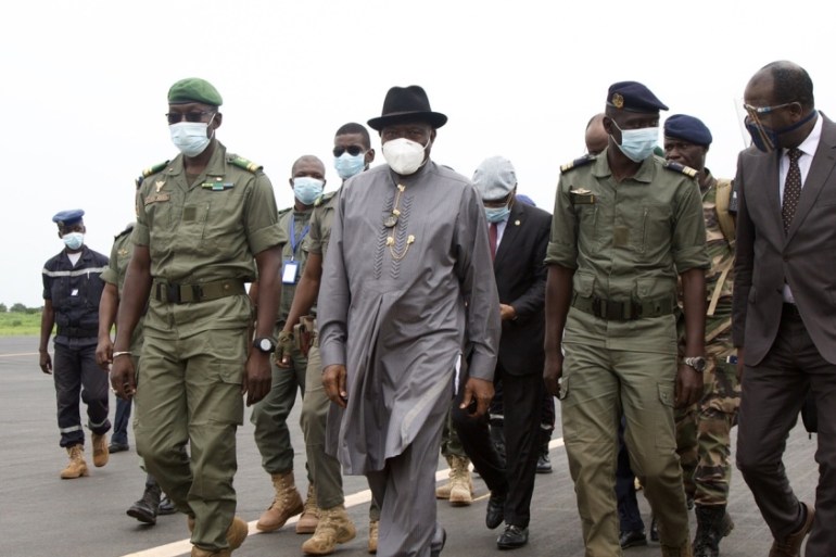 Former Nigerian President Goodluck Jonathan (2L) walks at the International Airport in Bamako upon his arrival on August 22, 202