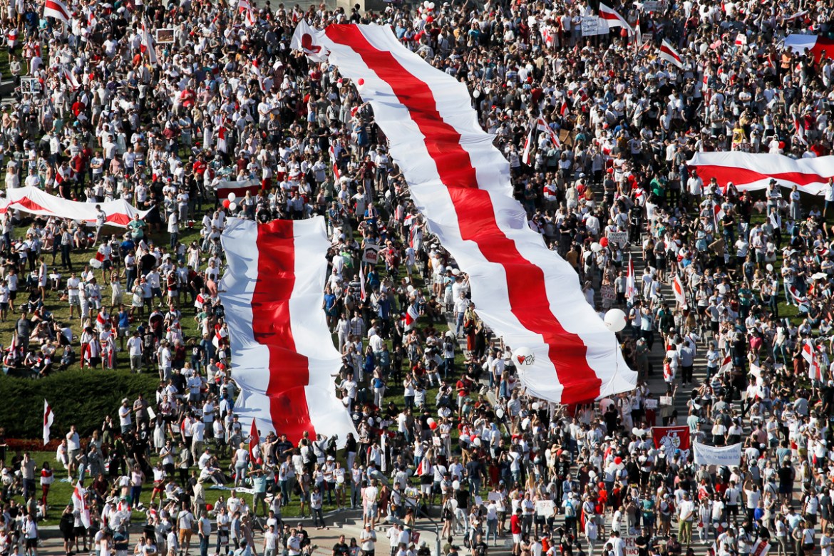 Belarusian opposition supporters rally with huge old Belarusian national flags in the center of Minsk, Belarus, Sunday, Aug. 16, 2020. Opposition supporters whose protests have convulsed the country f