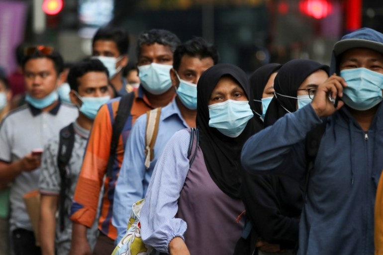 Passengers wearing protective masks wait in line to board a bus at a bus station, amid the coronavirus disease (COVID-19) outbreak in Kuala Lumpur