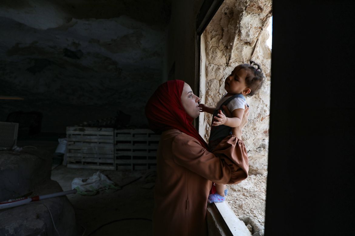 The wife of Ahmed Amarneh holds her daughter at their home built in cave, in the village of Farasin, west of Jenin, in the northern occupied West Bank on August 4, 2020. - Amarneh, a 30 year old civil