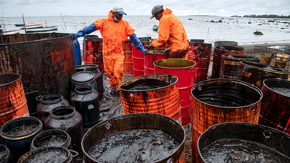 Workers collect leaked oil at the beach in Riviere des Creoles on August 15, 2020, due to the oil leaked from vessel MV Wakashio, belonging to a Japanese company but Panamanian-flagged, that ran agrou
