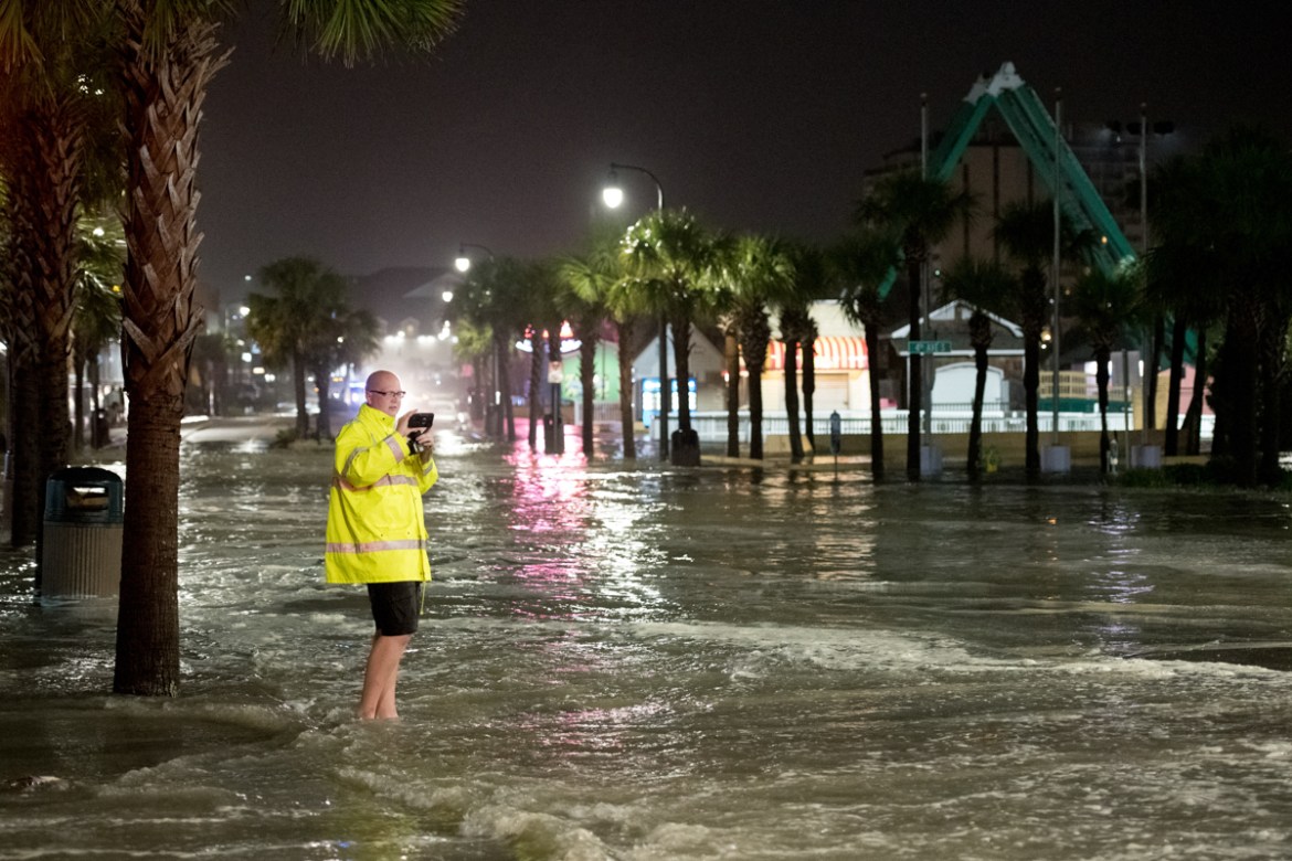 MYRTLE BEACH, SC - AUGUST 3: A man uses his phone to record video of floodwaters on Ocean Blvd. August 3, 2020 in Myrtle Beach, South Carolina. Hurricane Isaias continued to move north along the U.S.