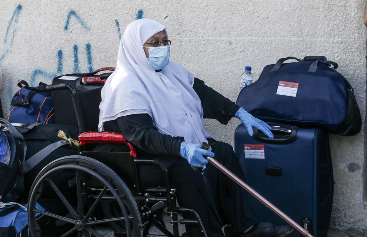 A Palestinian woman waits next to her luggage to leave Rafah border crossing with Egypt after months of closure due to the coronavirus pandemic in the southern Gaza Strip, on August 11, 2020. (Photo b