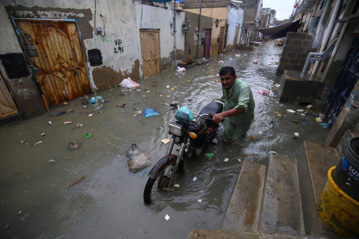 epa08625170 A man with his motercycle wades through rain water after heavy rains in Karachi, Pakistan, 25 August 2020. Sindh provincial government declared rain emergency after heavy monsoon rain floo
